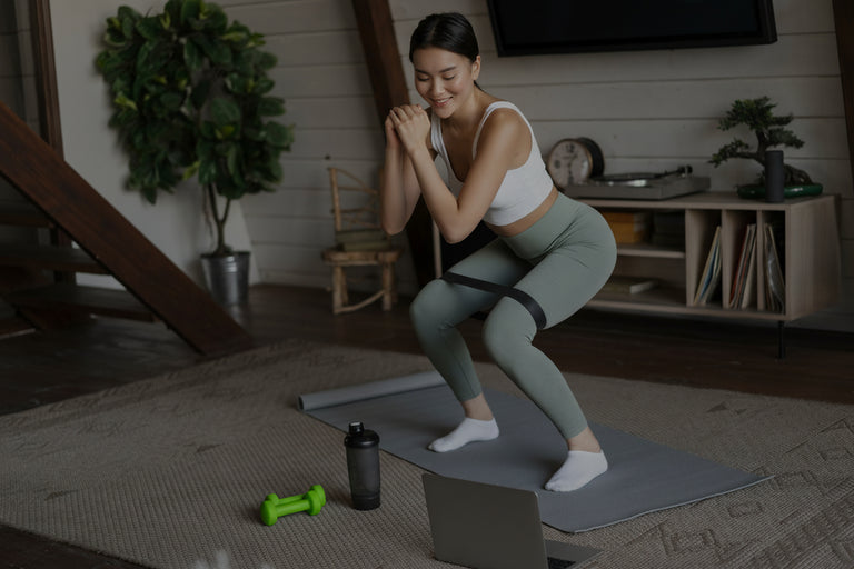 Woman exercising on a mat in a home setting with fitness equipment around